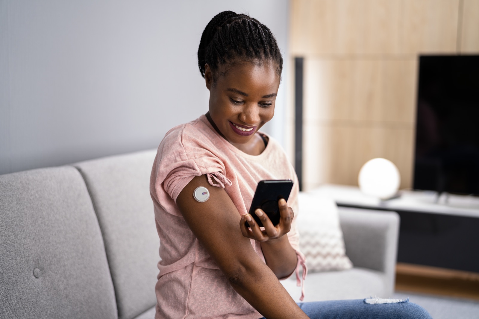 A person checks their CKM companion app while wearing the on-body sensor